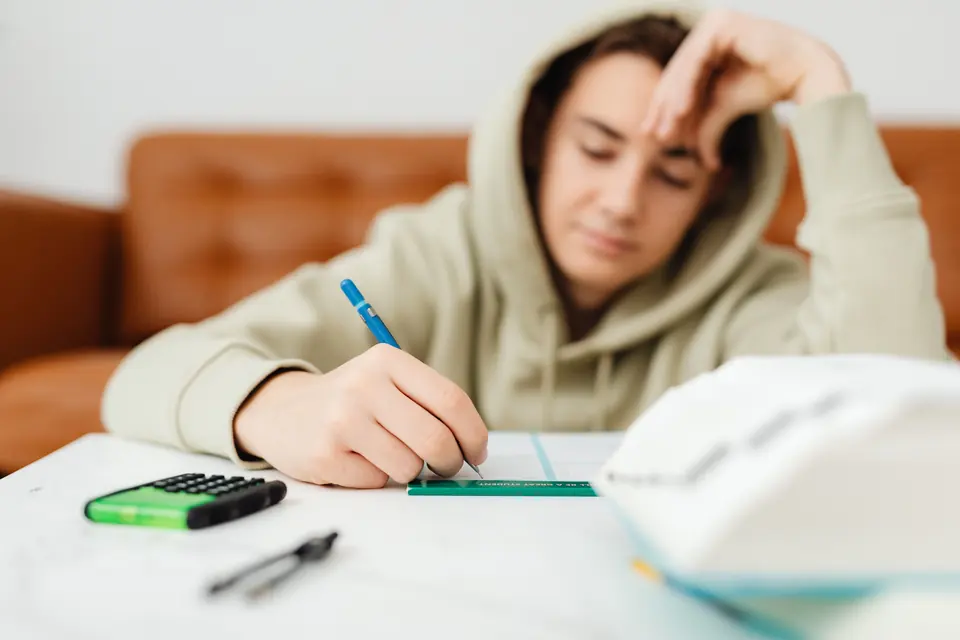 Jugendlicher schreibt konzentriert in seinen Lernunterlagen
